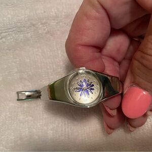 Ladie’s silver bracelet watch with purple flower in center. Works great!